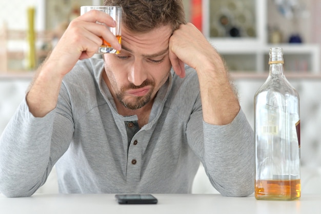 Jeune homme buvant de l'alcool, de mauvaise humeur