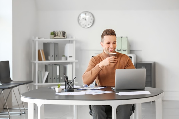 Jeune homme buvant du café tout en travaillant au bureau