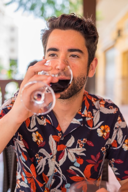 Jeune homme buvant du vin au restaurant