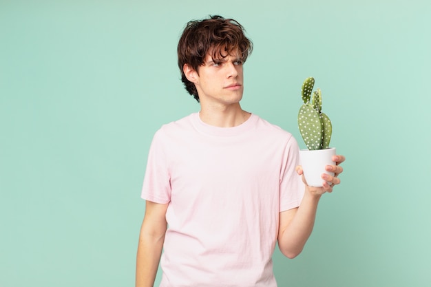 Jeune homme avec un cactus se sentant triste, contrarié ou en colère et regardant sur le côté