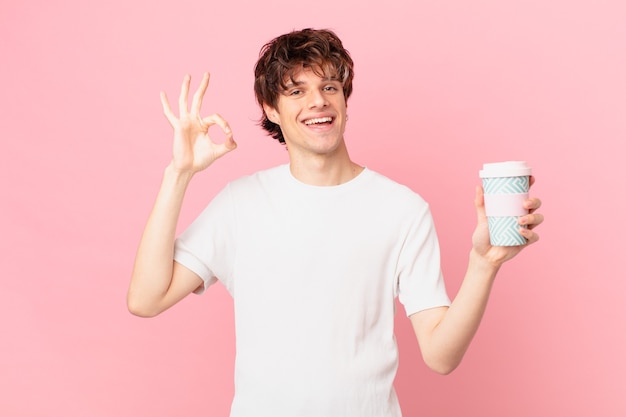 Jeune homme avec un café se sentant heureux, montrant son approbation avec un geste correct