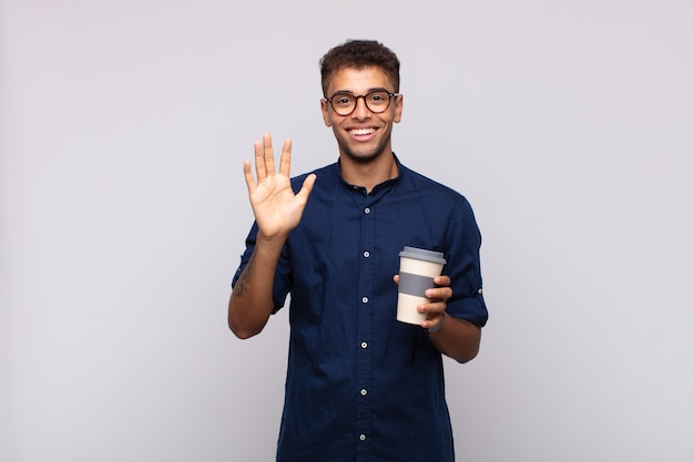 Jeune homme avec un café souriant et à la sympathique, montrant le numéro cinq ou cinquième avec la main en avant, compte à rebours