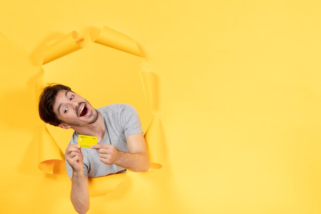 jeune homme avec carte de crédit sur fond jaune argent shopping vente