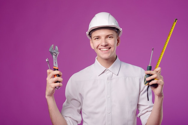 Jeune Homme En Casque Blanc Avec Outil De Travail à La Main Sur Fond Violet