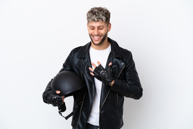 Jeune homme avec un casque de moto isolé sur fond blanc souriant beaucoup