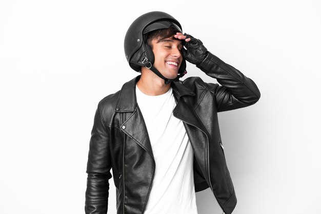 Jeune homme avec un casque de moto isolé sur fond blanc souriant beaucoup