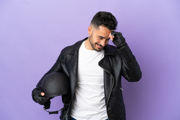 Jeune homme avec un casque de moto isolé sur fond violet en riant