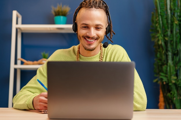 Jeune homme avec casque regardant la caméra de l'ordinateur portable. Concept de consultant de service