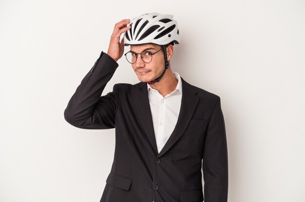 Jeune homme caucasien d'affaires tenant un casque de vélo isolé sur fond blanc étant choqué, elle s'est souvenue d'une réunion importante.