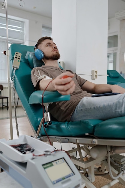 Un jeune homme caucasien assis dans un fauteuil pendant une transfusion sanguine