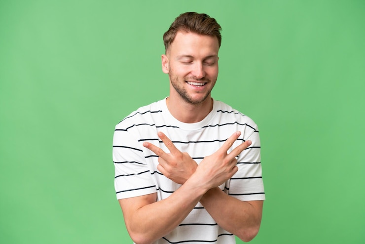 Photo un jeune homme caucasien blond sur un fond isolé souriant et montrant un signe de victoire