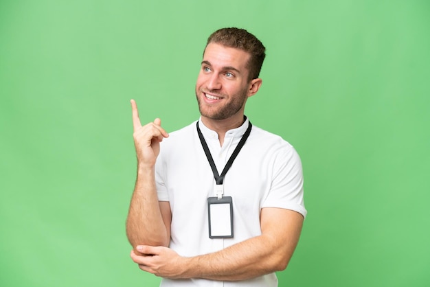 Jeune homme caucasien avec carte d'identité isolé sur fond vert chroma pointant vers une excellente idée