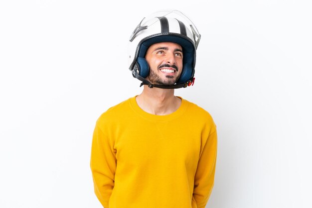 Jeune homme caucasien avec un casque de moto isolé sur fond blanc en pensant à une idée tout en levant les yeux