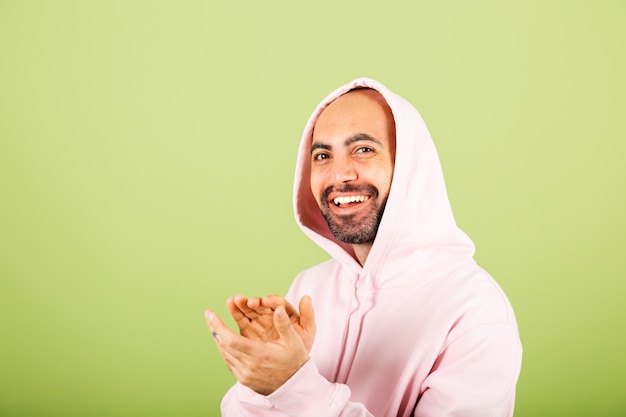 Jeune homme caucasien chauve en sweat à capuche rose isolé, heureux applaudissant et applaudissant heureux et joyeux, souriant mains fières ensemble