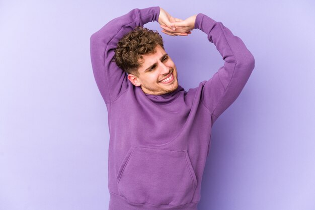 Jeune homme caucasien cheveux bouclés blonds, étirement des bras, position détendue.