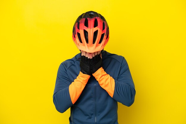 Jeune homme caucasien cycliste isolé sur fond jaune avec une expression fatiguée et malade