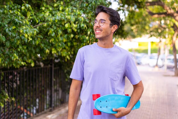 Jeune homme caucasien dans un parc avec un skate