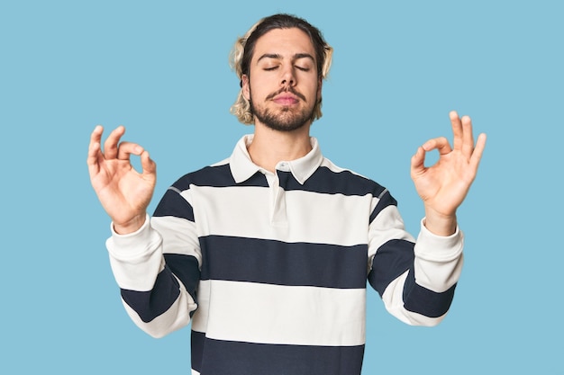 Un jeune homme caucasien dans un studio se détend après une dure journée de travail. Elle fait du yoga.