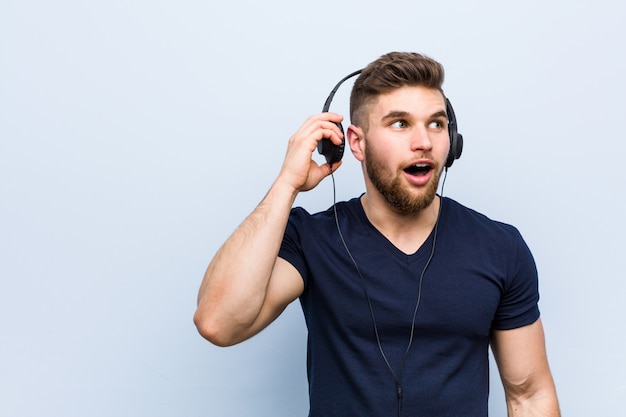 Jeune homme caucasien, écouter de la musique en essayant d'écouter un commérage