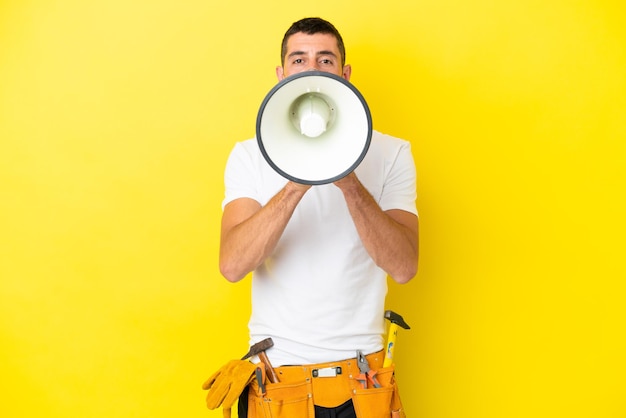 Jeune homme caucasien électricien isolé sur fond jaune criant à travers un mégaphone