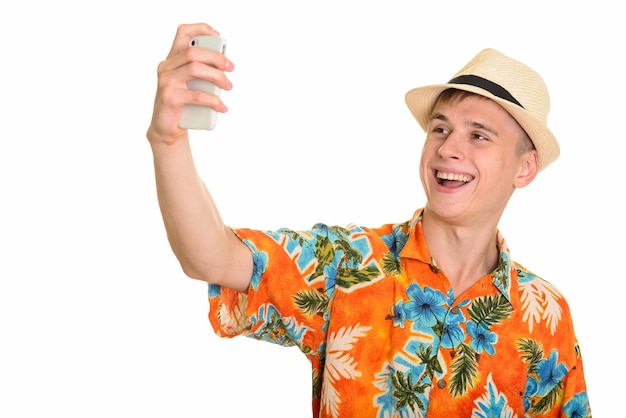 Jeune homme caucasien heureux souriant et prenant selfie avec mobile