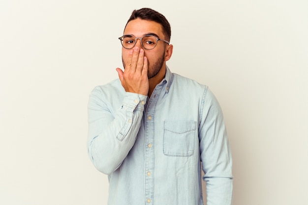 Jeune homme caucasien isolé sur blanc choqué, couvrant la bouche avec les mains, impatient de découvrir quelque chose de nouveau.