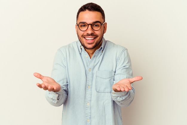 Jeune homme caucasien isolé sur blanc recevant une agréable surprise, excité et levant les mains.