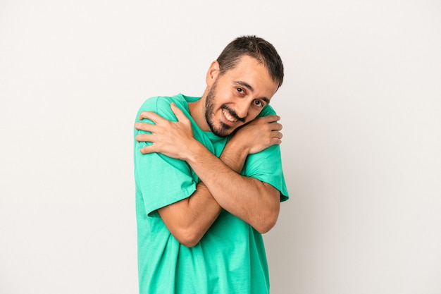 Jeune homme caucasien isolé sur fond blanc câlins, souriant insouciant et heureux.