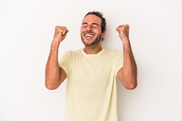 Jeune homme caucasien isolé sur fond blanc célébrant une victoire, une passion et un enthousiasme, une expression heureuse.