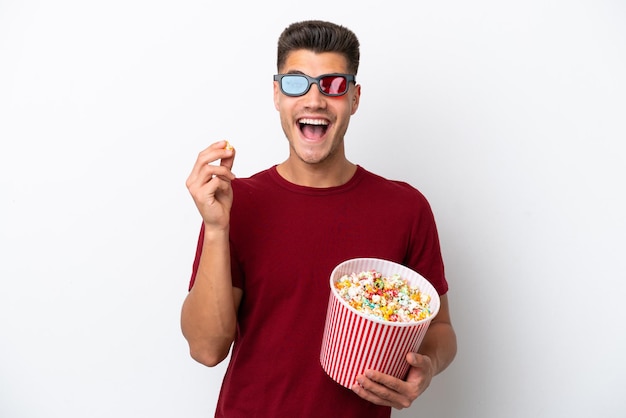 Jeune homme caucasien isolé sur fond blanc avec des lunettes 3d et tenant un grand seau de pop-corn