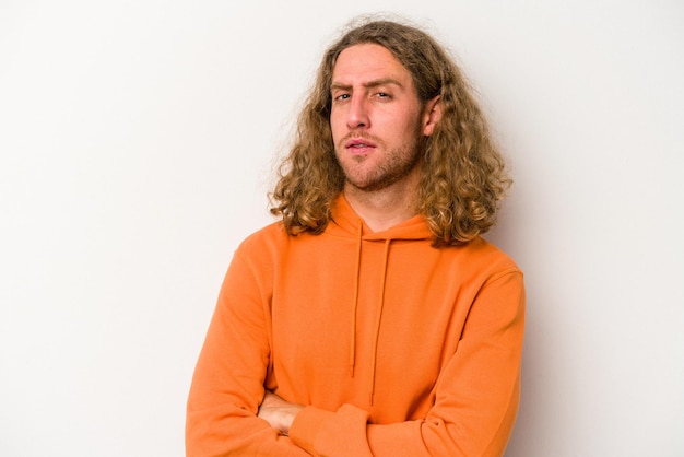 Jeune homme caucasien isolé sur fond blanc malheureux regardant à huis clos avec une expression sarcastique