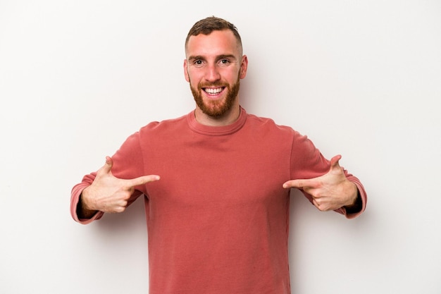 Jeune homme caucasien isolé sur fond blanc pointe vers le bas avec les doigts, sentiment positif.