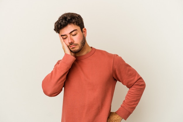 Jeune homme caucasien isolé sur fond blanc qui s'ennuie, est fatigué et a besoin d'une journée de détente.