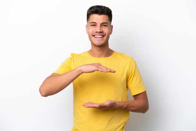 Jeune homme caucasien isolé sur fond blanc tenant un fond imaginaire sur la paume pour insérer une annonce