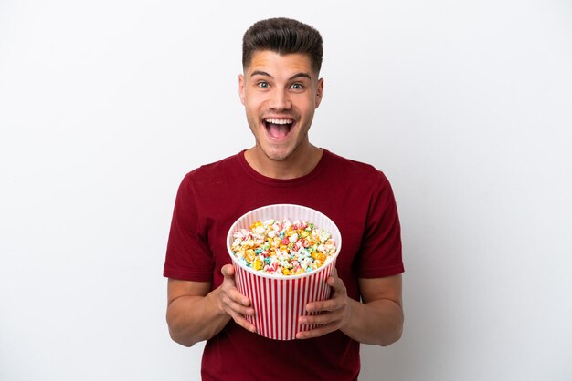 Jeune homme caucasien isolé sur fond blanc tenant un grand seau de pop-corn