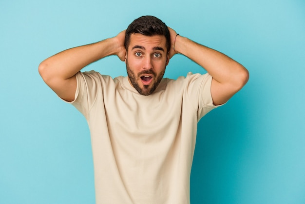 Jeune homme caucasien isolé sur fond bleu criant, très excité, passionné, satisfait de quelque chose.