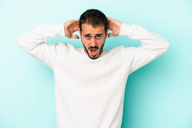 Jeune homme caucasien isolé sur fond bleu criant, très excité, passionné, satisfait de quelque chose.