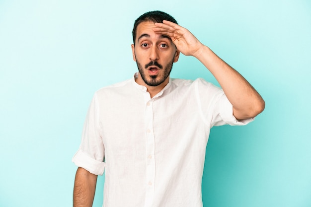 Jeune homme caucasien isolé sur fond bleu crie fort, garde les yeux ouverts et les mains tendues.