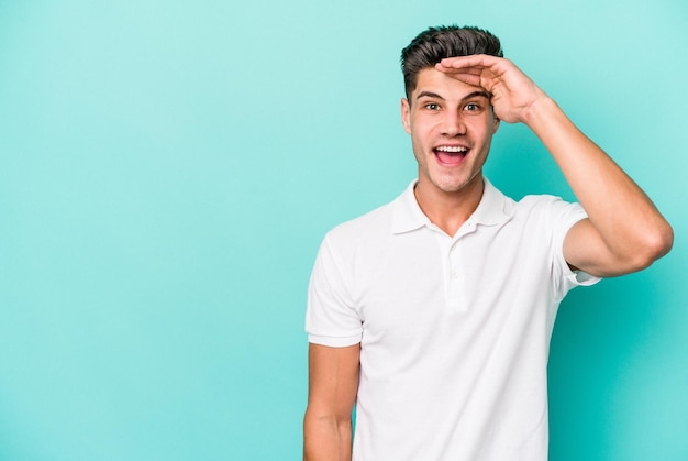 Jeune homme caucasien isolé sur fond bleu crie fort, garde les yeux ouverts et les mains tendues.