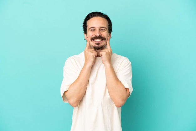 Jeune homme caucasien isolé sur fond bleu souriant avec une expression heureuse et agréable