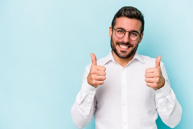 Jeune homme caucasien isolé sur fond bleu souriant et levant le pouce vers le haut