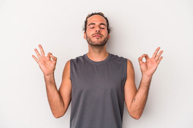 Jeune homme caucasien isolé sur fond gris se détend après une dure journée de travail, elle fait du yoga.