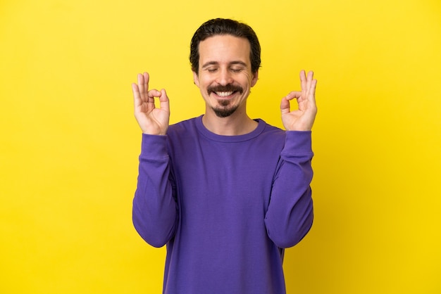 Jeune homme caucasien isolé sur fond jaune dans une pose zen