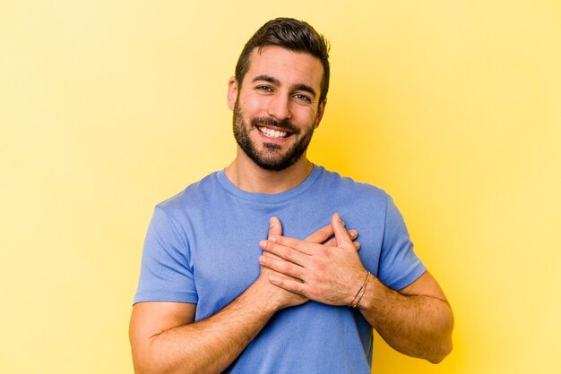 Jeune homme caucasien isolé sur fond jaune a une expression amicale en appuyant sur la paume contre la poitrine Concept d'amour