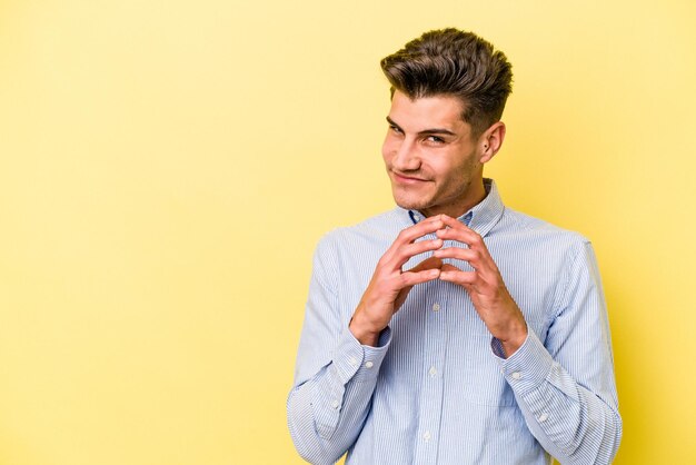 Jeune homme caucasien isolé sur fond jaune faisant un plan à l'esprit la mise en place d'une idée