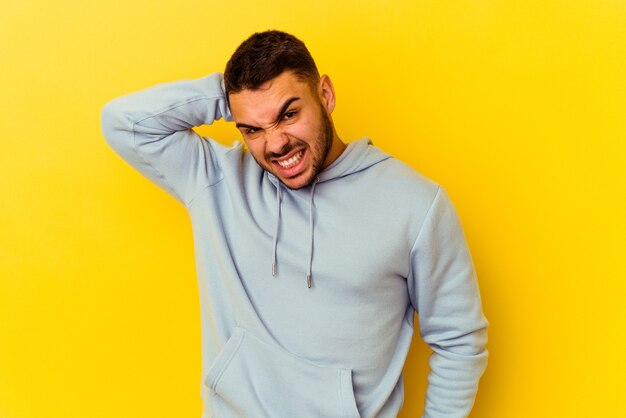 Jeune homme caucasien isolé sur fond jaune fatigué et très endormi en gardant la main sur la tête.