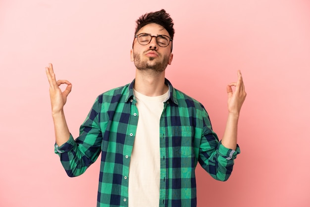 Jeune homme caucasien isolé sur fond rose dans une pose zen