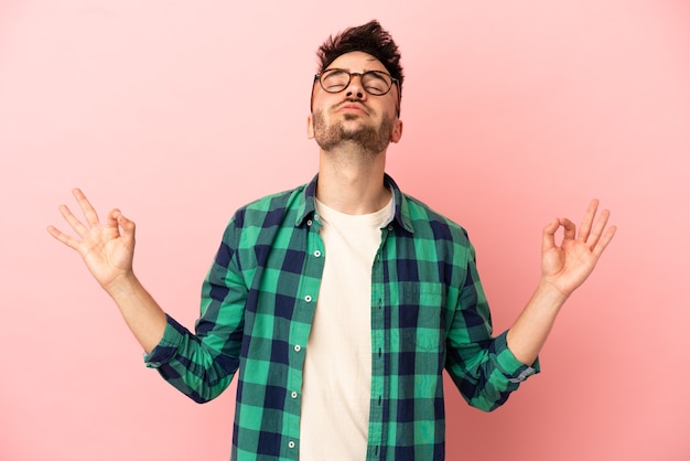 Jeune homme caucasien isolé sur fond rose dans une pose zen