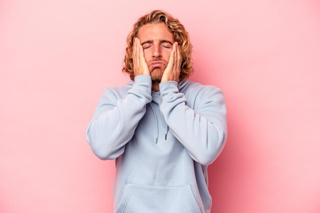 Jeune homme caucasien isolé sur fond rose pleurnichant et pleurant tristement.