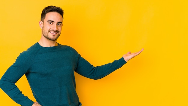 Jeune homme caucasien isolé sur jaune montrant une expression bienvenue.